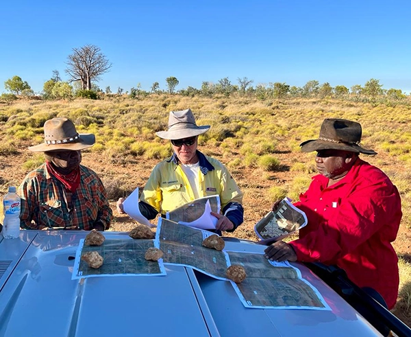 Traditional Owners and Black Mountain Energy staff reviewing survey maps on a vehicle bonnet